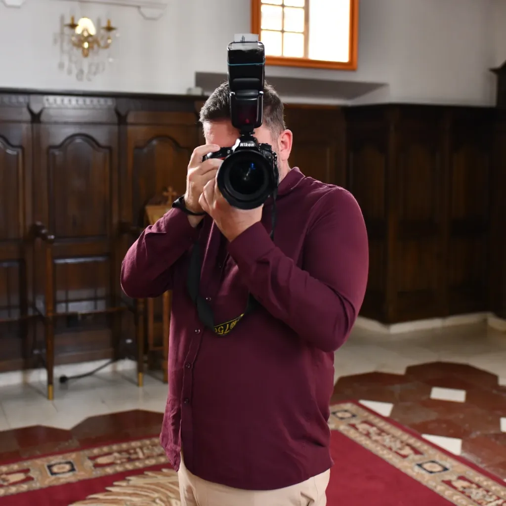 Njegoš Tomić fotografiše, sa fotoaparatom podignutim ispred lica.